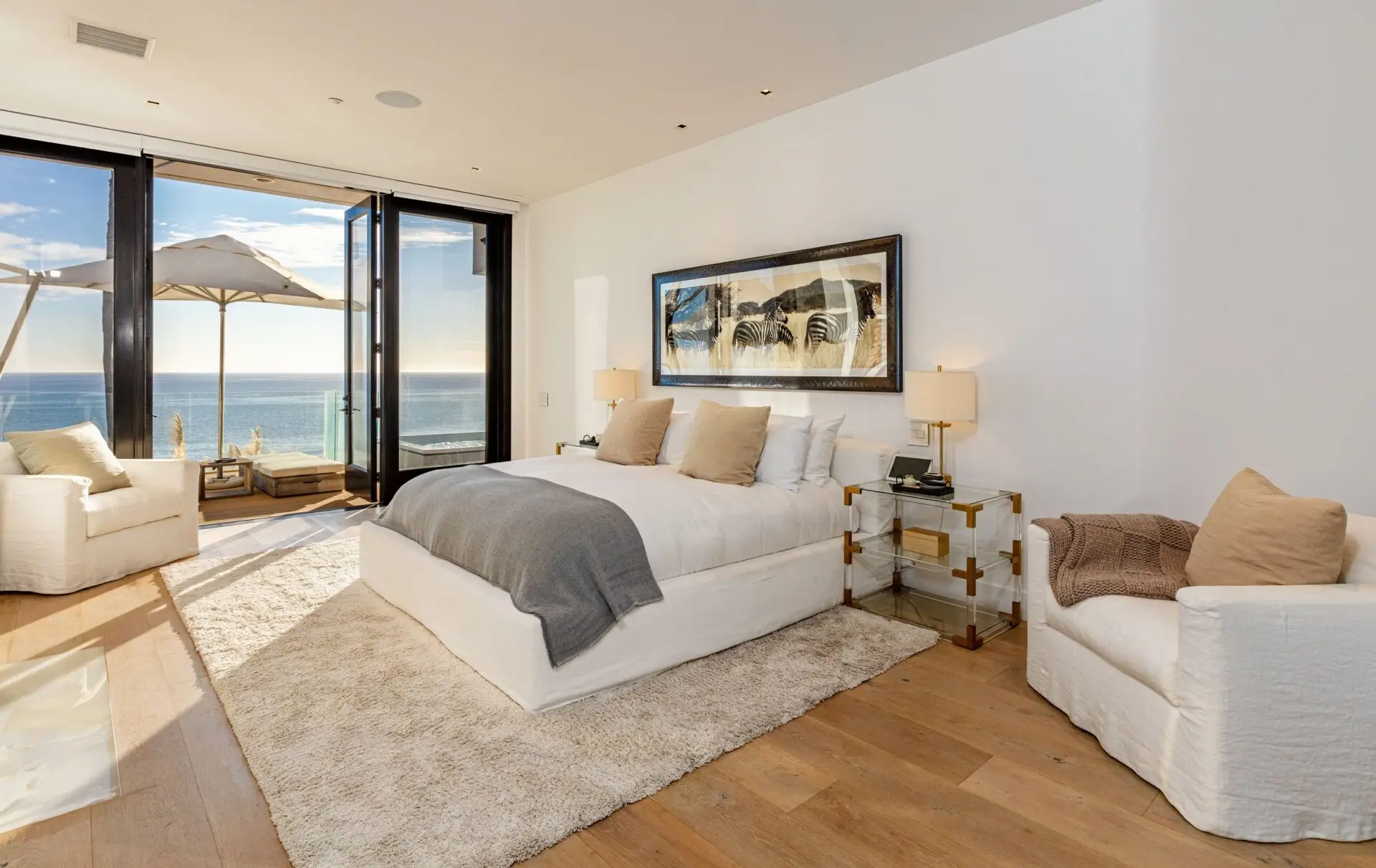 A quiet bedroom in the Malibu house, glass doors open to the deck and the ocean beyond