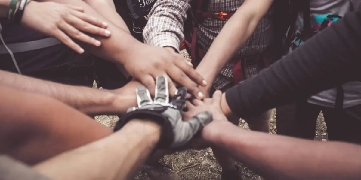 A group of people stacking their hands together outdoors