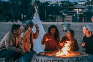 Friends Telling Stories in Front of a Camp Fire on a Beach