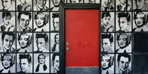 Pop art portraits of iconic figures in a striking black-and-white style with a vibrant red door.