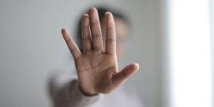 lose-up of hand outstretched in "stop" gesture, person blurred in background.