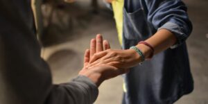 Two people joining hands in a gesture of support and connection.