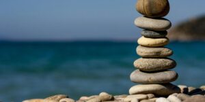 A stack of balanced rocks against a tranquil turquoise ocean and sky.