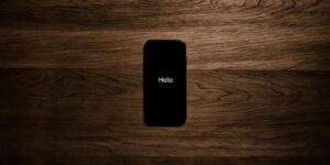 Smartphone displaying 'Hello' message centered on dark wooden surface