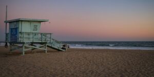 Lifeguard tower seventeen stands on beach at sunset with pink and purple sky