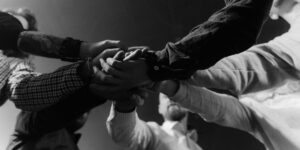 Multiple hands joining together in unity, captured in dramatic black and white perspective