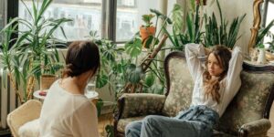 Person relaxing on vintage floral couch while meeting with their sober coach amidst houseplants