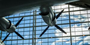 A view from below of vintage aircraft propellers mounted indoors, with natural light streaming through large glass panels—highlighting aviation history and engineering at a museum exhibit.