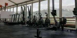 Luxury rehab fitness center with treadmills, bikes, and mountain views through floor-to-ceiling windows