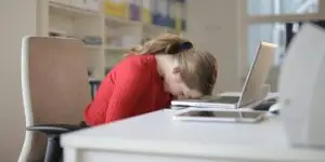 Exhausted person with head on desk, showing signs of burnout and emotional overwhelm often experienced before entering addiction recovery.