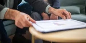 A close-up view of a financial counselor and a client reviewing paperwork and documents together on a small table, representing the process of verifying PPO health insurance benefits and planning coverage for medically supervised drug detoxification.