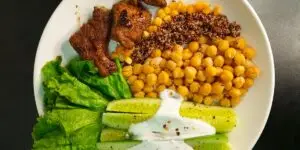 A top-down view of a balanced, healthy meal featuring lean protein, chickpeas, quinoa, and fresh greens, illustrating the essential nutrients and amino acids needed to help restore brain chemistry and support holistic physical healing after substance use.