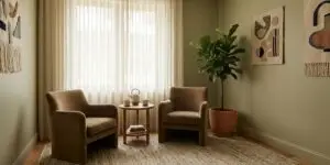 Warm private therapy room with two armchairs, soft natural light, and calming earth tones.