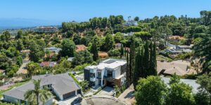 An aerial view of a magnificent, modern luxury estate nestled among lush green trees and quiet rolling hills in Beverly Hills, California, illustrating the highly private, serene, and exclusive environment that makes it an ideal setting for luxury addiction recovery.